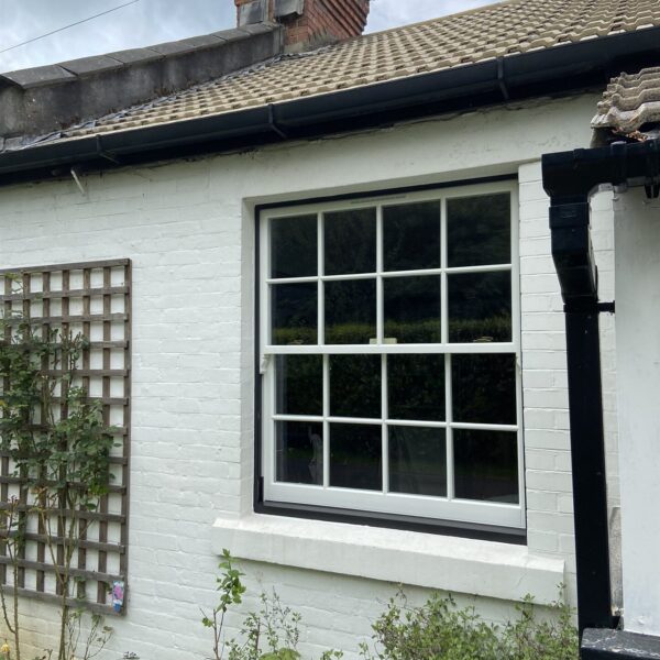 Timber sliding sash window with glazing bars on a white cottage, Woldingham, Surrey