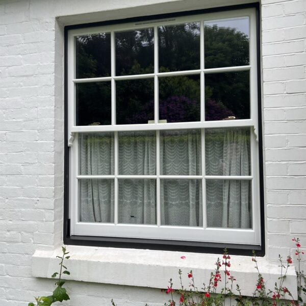New timber sash window with black frame on a white brick cottage, Woldingham, Surrey